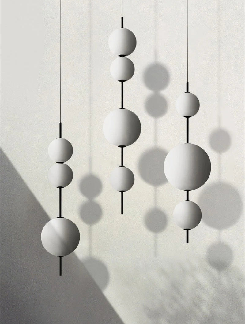 Modern pendant light with white spherical shades on a neutral background