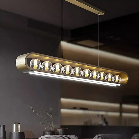 Close-up of a modern gold pendant light featuring clear glass spheres and a brushed gold finish, suspended by thin wires.