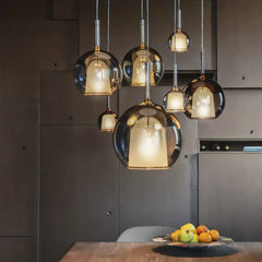 A cluster of globe pendant lights with rose gold finish and clear glass shades hanging over a wooden table.