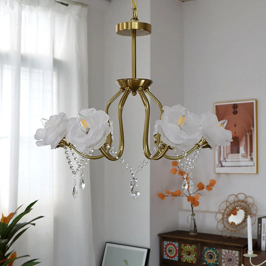 White rose lampshades on a gold chandelier with crystal pendants, displayed in a well-lit room setting.