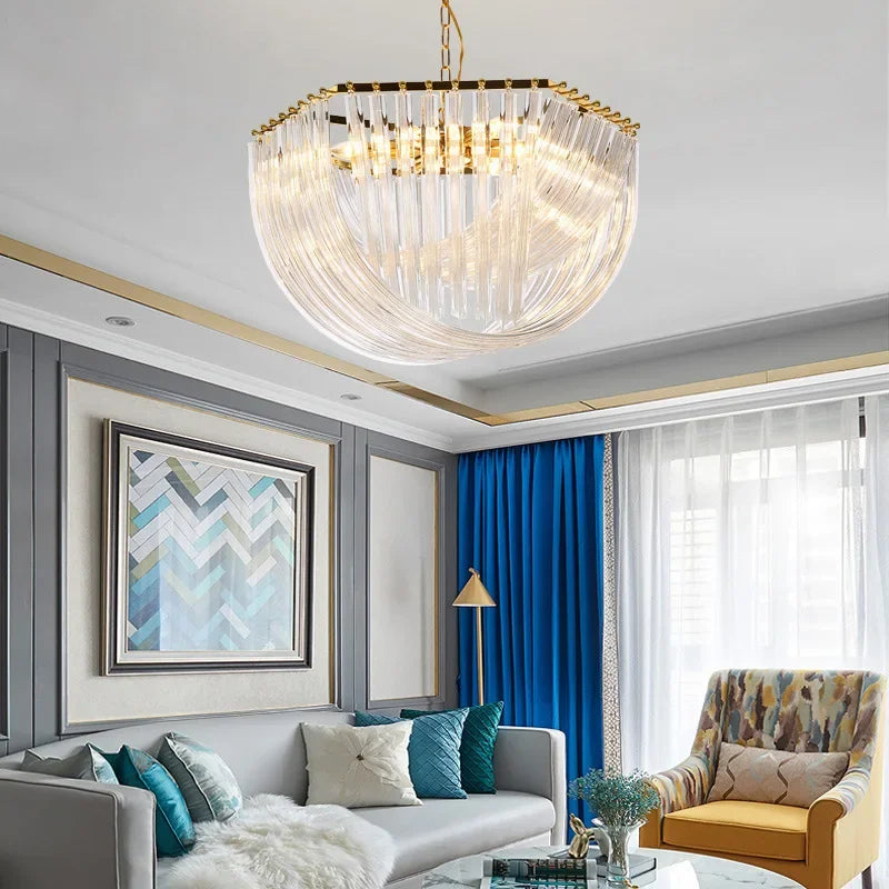 Gold crystal waterfall chandelier with cascading clear glass tubes and a polished gold frame, illuminating a modern living room.