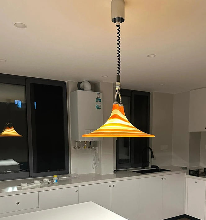 Modern kitchen with white cabinets, a hanging pendant light, and a television.