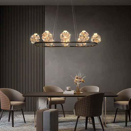 Gold linear pendant light with multiple crystal orb lights hanging over a dining table.