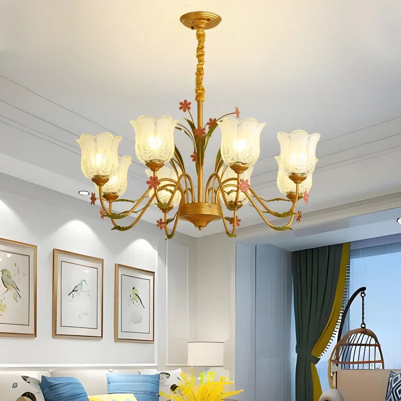 Gold floral chandelier hanging above a sofa in a living room with framed artwork.