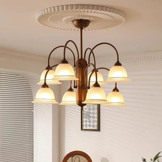 A multi-angle view of a brushed gold chandelier with multiple frosted glass bell-shaped shades, showcasing its intricate arm structure and central column.