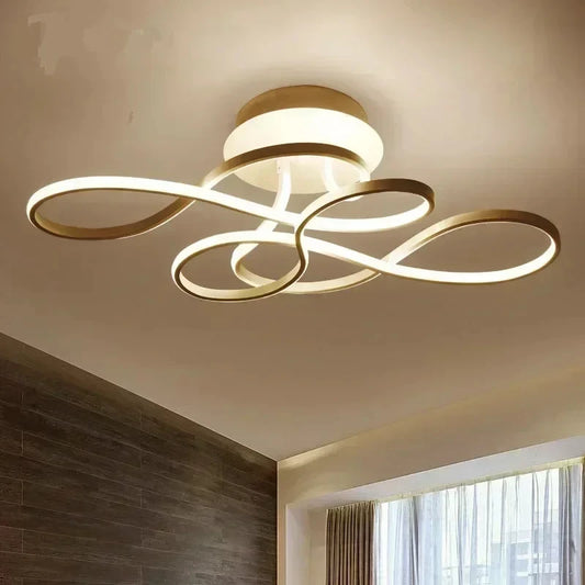 Ceiling view of a modern gold swirl flush mount light with integrated LED lighting against a white ceiling.