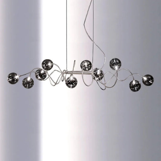 Chrome spiral wave pendant light with multiple smoky gray glass globes suspended against a white background.