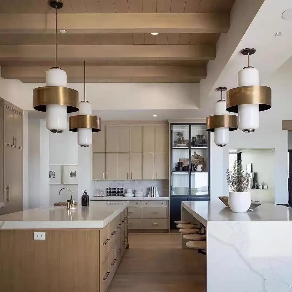 Interior view of a modern kitchen with a long island and several pendant lights hanging above.