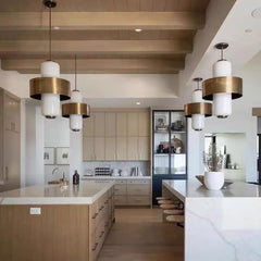 Interior view of a modern kitchen with a long island and several pendant lights hanging above.