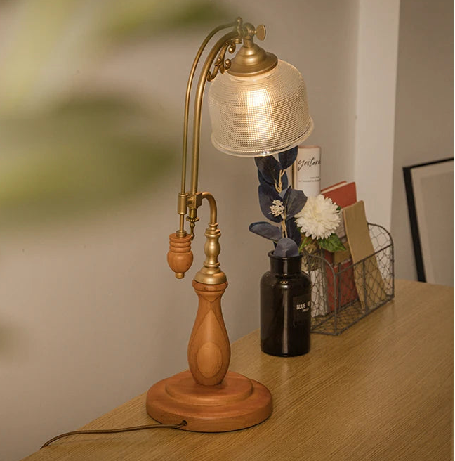 Wooden and brass table lamp on a wooden surface with a blurred background