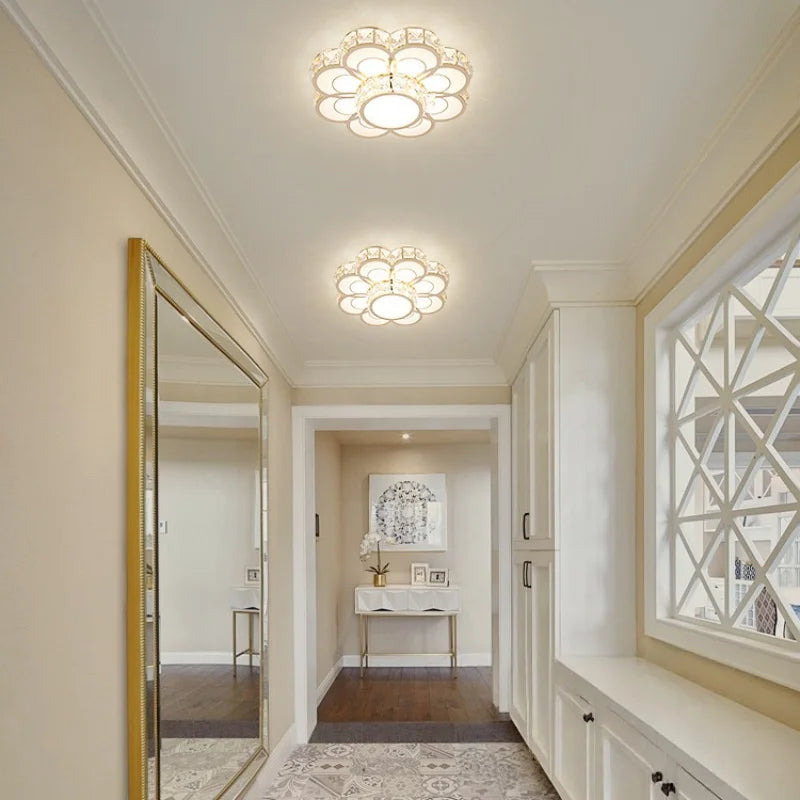 A hallway with gold and crystal flush mount ceiling lights and a large decorative mirror.
