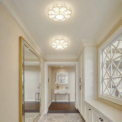 A hallway with gold and crystal flush mount ceiling lights and a large decorative mirror.