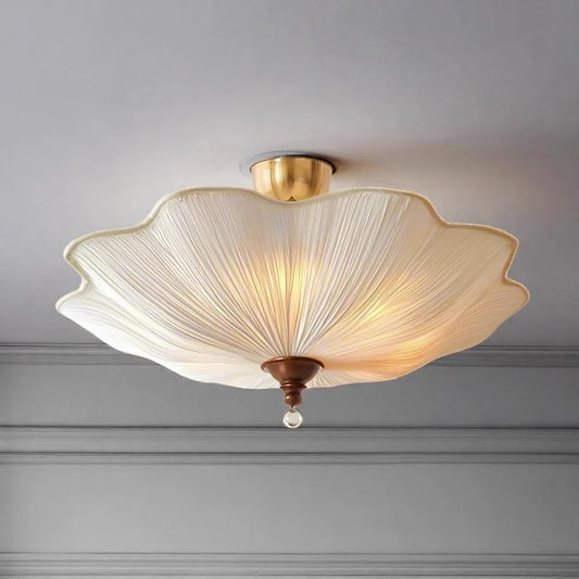 White fabric lotus-shaped ceiling light with a polished gold finish, illuminated and mounted on a neutral ceiling.