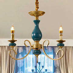 A smaller version of the gold candelabra chandelier with teal ceramic details hanging in a room.