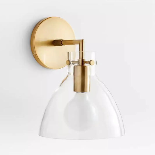 Gold-finished wall sconce with a clear glass dome shade and exposed LED bulb against a white background.