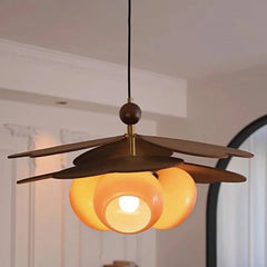 Modern pendant light with wooden design and orange glass shade in a room setting.