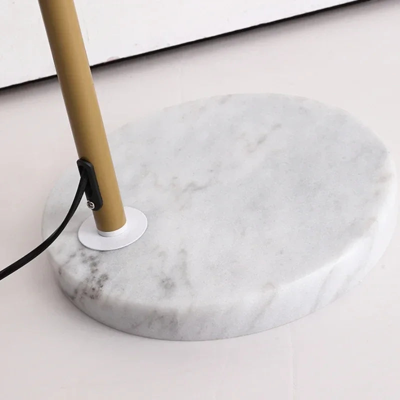 Marble base of a lamp with gold pole on a light background