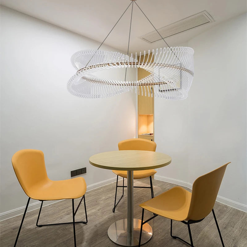 Modern dining area with a round table and yellow chairs under a unique ceiling light fixture.