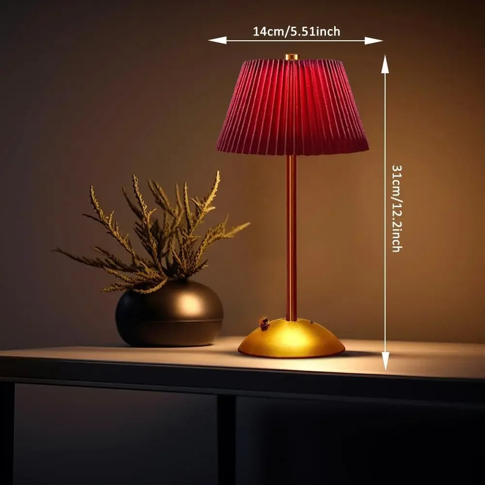Red lamp with gold base on a table next to a plant, with measurements indicated.