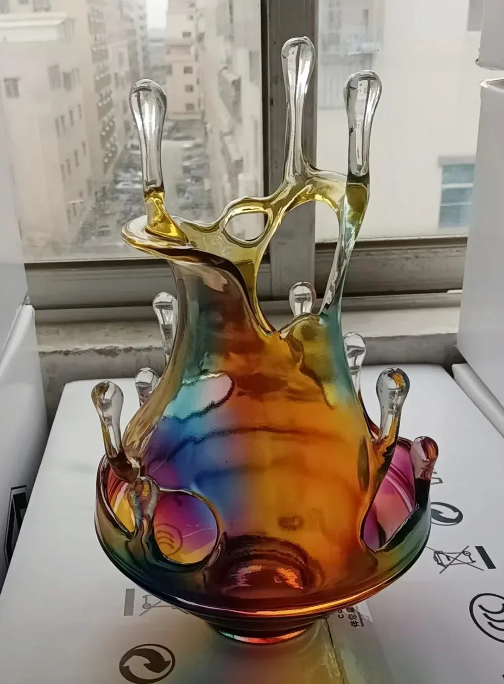 Colorful glass sculpture on a white surface with a window in the background