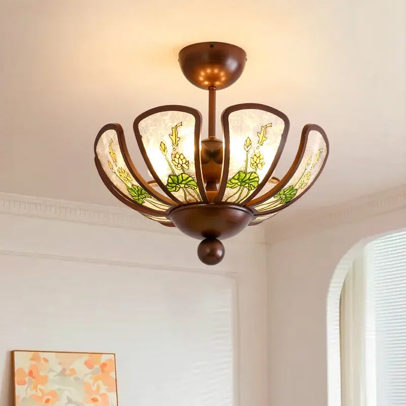 Close-up of a matte bronze pendant light with a flower-shaped design and green floral glass panels.