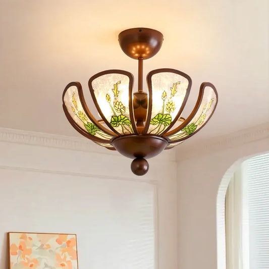 Close-up of a matte bronze pendant light with a flower-shaped design and green floral glass panels.