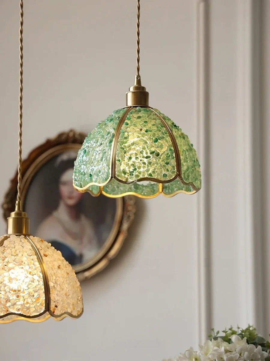 Decorative pendant lights with green and gold glass shades hanging against a neutral wall.