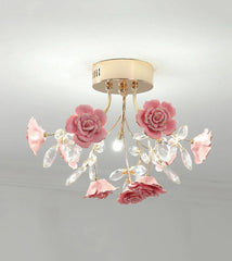 A close-up view of a pink ceramic rose and crystal embellishments on a gold flush mount ceiling light.