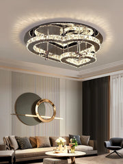 A bright living room with a large window, showcasing a heart-shaped crystal chandelier mounted on the ceiling.