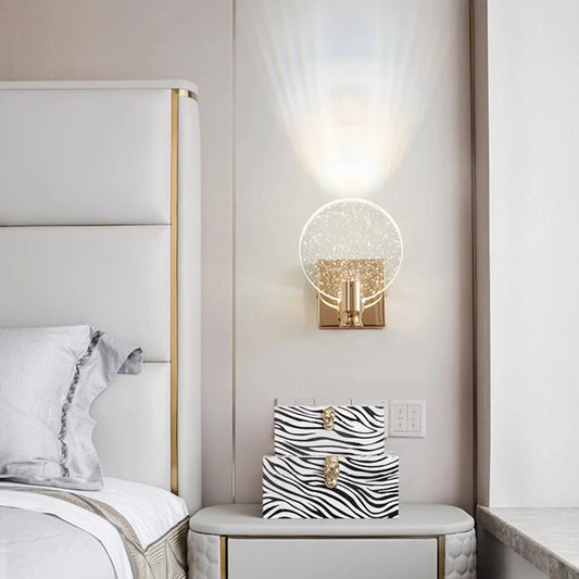 A gold and clear bubble crystal wall sconce installed above a bedside table with zebra print decorative boxes in a bedroom setting.