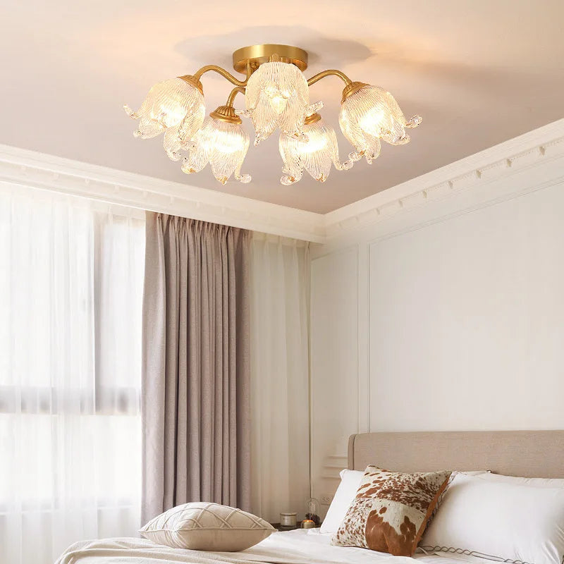 A bedroom scene featuring a gold semi-flush ceiling light with glass floral shades illuminating the space.