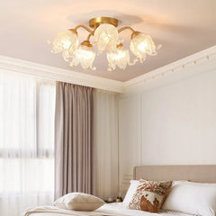 A bedroom scene featuring a gold semi-flush ceiling light with glass floral shades illuminating the space.