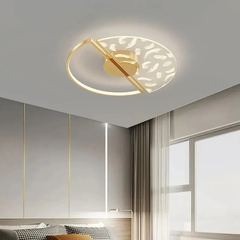 Gold and white circular ceiling light with feather pattern glass shade and gold frame, mounted on a grey ceiling.