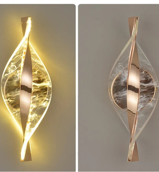 Two modern wall sconces with a leaf-like design on a neutral background