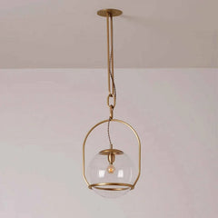A gold metal frame surrounds a clear glass globe pendant light, suspended by a chain from a ceiling mount.