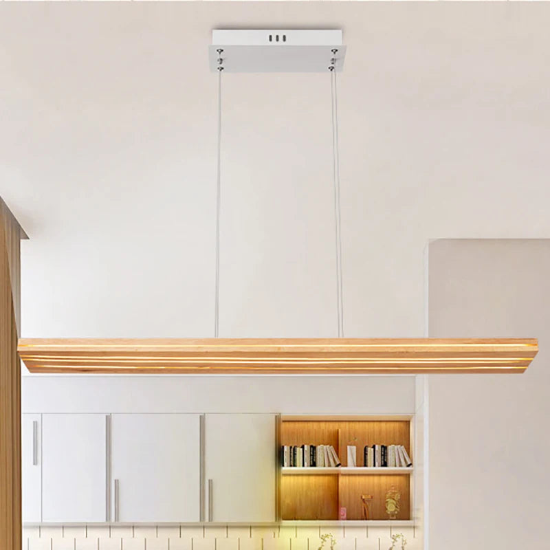 Modern pendant light fixture hanging above a kitchen counter with cabinets and books in the background.