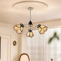 A polished chrome chandelier with three light beige, petal-shaped shades arranged in a floral pattern.
