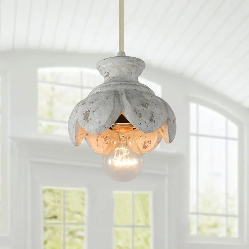 Close-up of a wood carved floral pendant light fixture showcasing the distressed finish and exposed bulb.