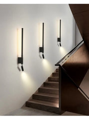 Multiple black adjustable LED wall sconces installed along a wooden staircase.