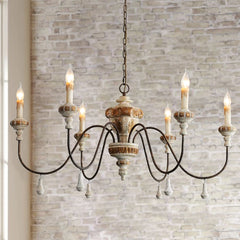 Close-up of a distressed wood and iron candle chandelier against a brick wall.