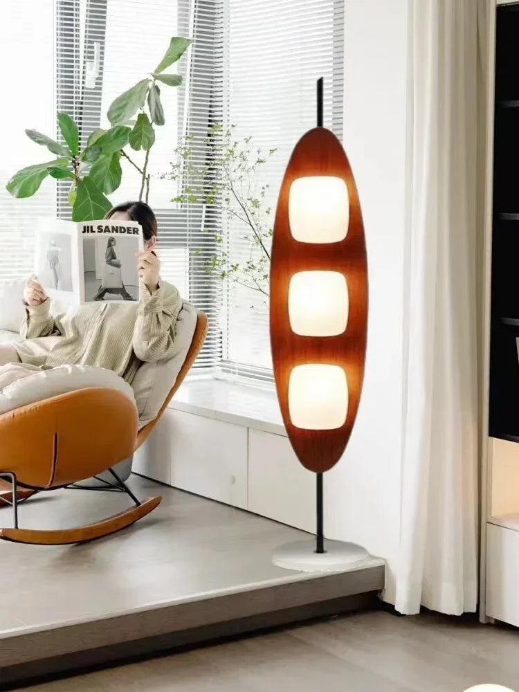 Modern living room with a unique floor lamp, rocking chair, and plant.