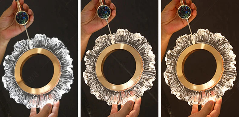 Decorative mirror with gold and silver design held by hands against a dark background