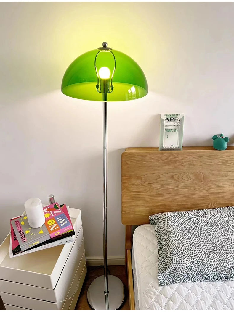 A green mushroom-shaped floor lamp casting a warm glow next to a bed with a wooden headboard.