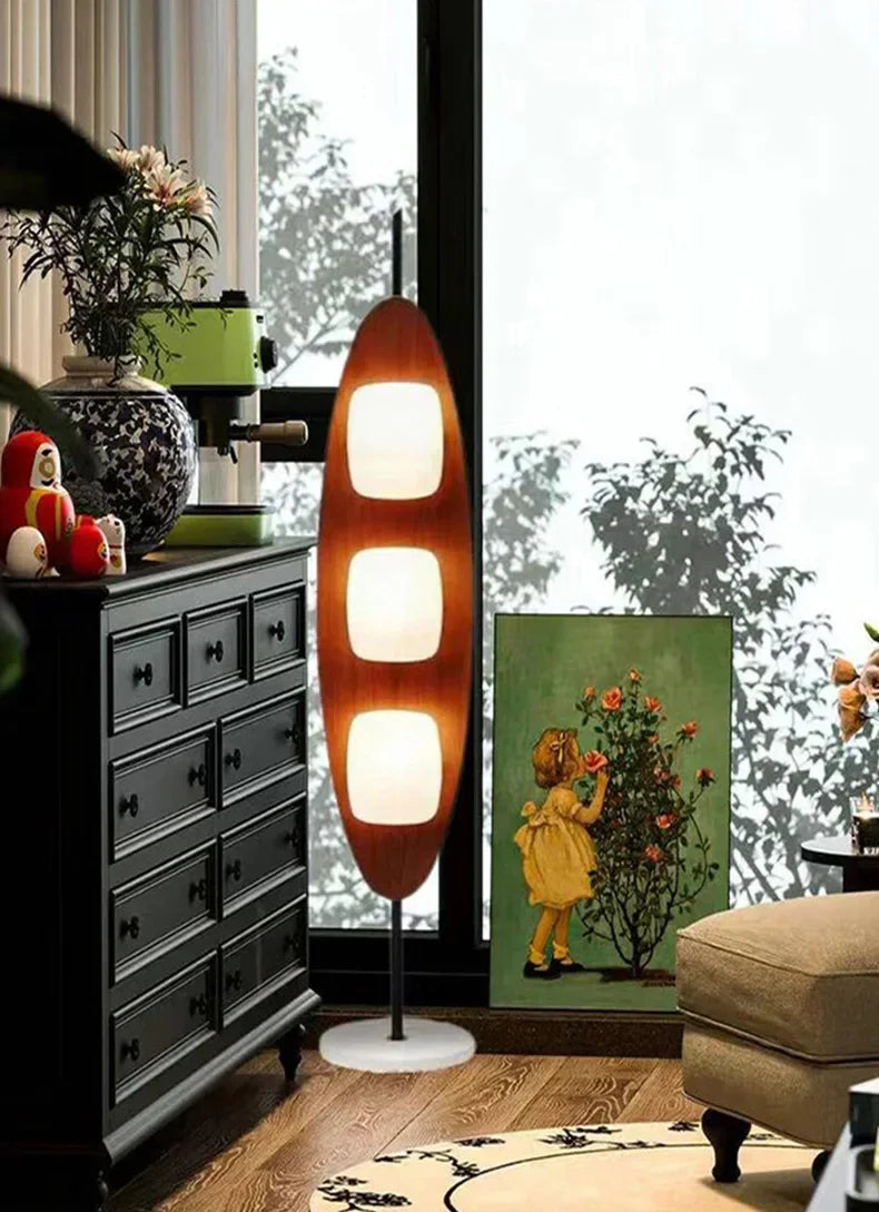Modern lamp in a living room with a dresser and artwork on the wall.