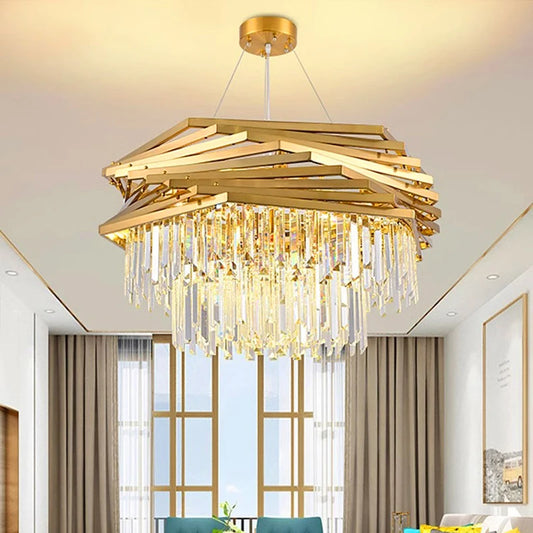 A gold tiered crystal chandelier hanging in a modern living room with large windows and beige curtains.