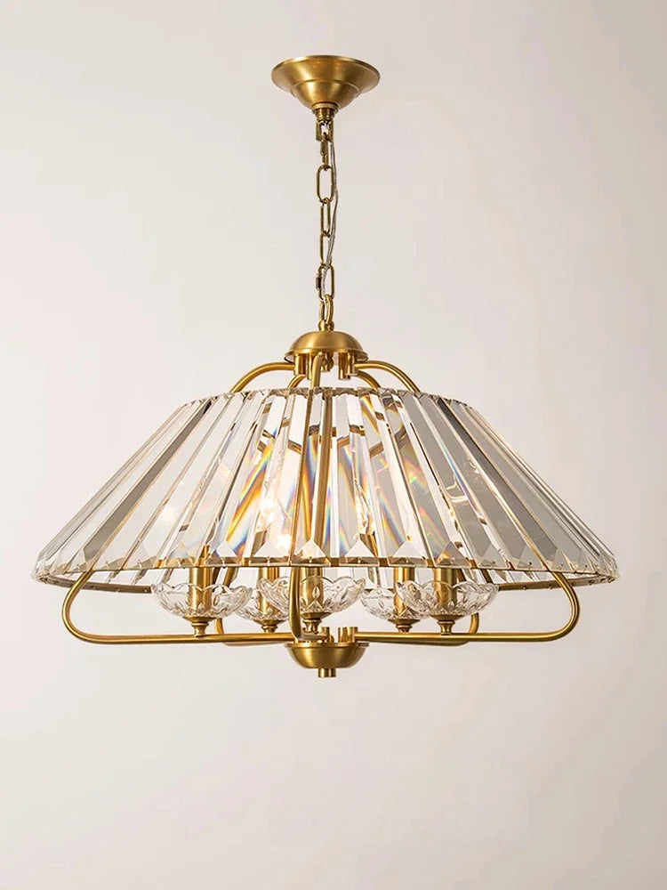 Close-up of a gold crystal faceted pendant light, showing the intricate detail of the crystal and metal frame.