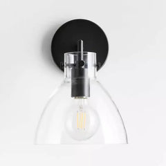 Black-finished wall sconce with a clear glass dome shade and an Edison-style LED bulb.