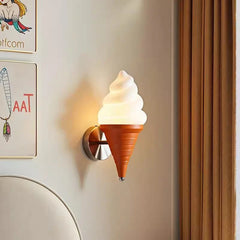 Close-up of an ice cream cone wall sconce mounted on a wall with artwork and curtains in the background.