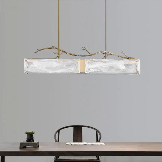 Close-up view of the rectangular glass shade and brushed gold branch detail on the pendant light.