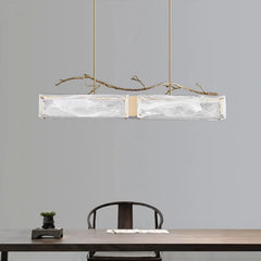 Close-up view of the rectangular glass shade and brushed gold branch detail on the pendant light.